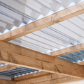 Wooden beams of a roof structure with a white corrugated material background
