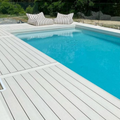 Poolside deck with striped cushions and a clear blue pool.