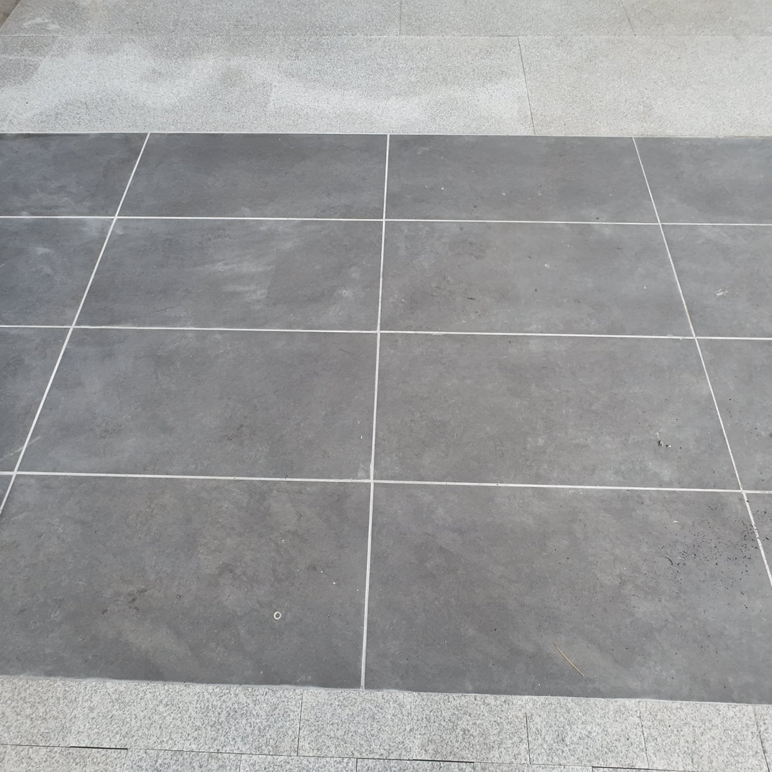 Gray tiled floor with a corner showing a step and wall.