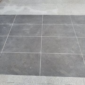 Gray tiled floor with a corner showing a step and wall.