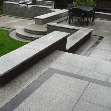 Outdoor patio with stone bench, fire pit, and dining area.