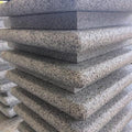 A stack of gray granite bullnose step corners with a flammed top and bullnosed edges.