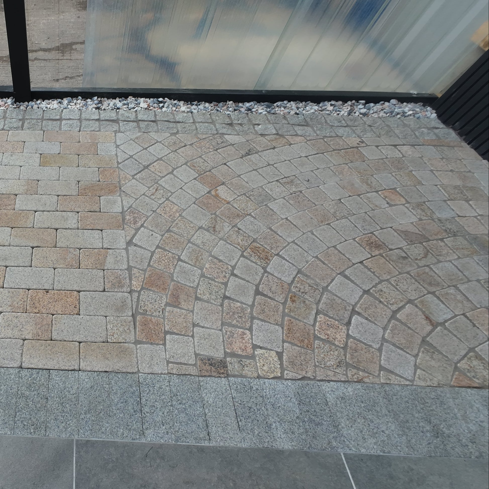 Paved area with stone tiles and a glass door in the background