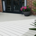 White wooden deck with a potted plant and a brick wall background